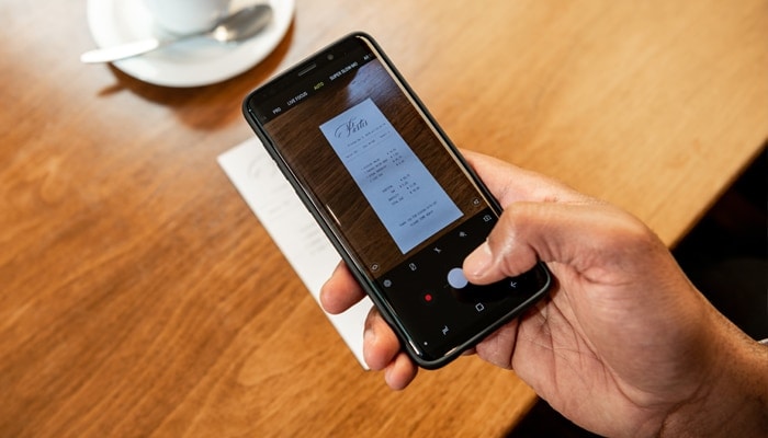 A person taking a photo of a receipt with a phone