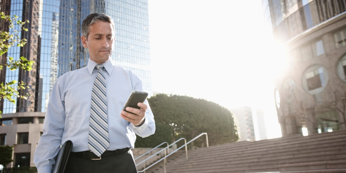 Businessman text messaging on mobile phone outdoors