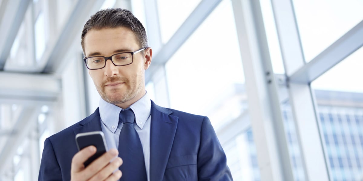 man looking at phone walking through office