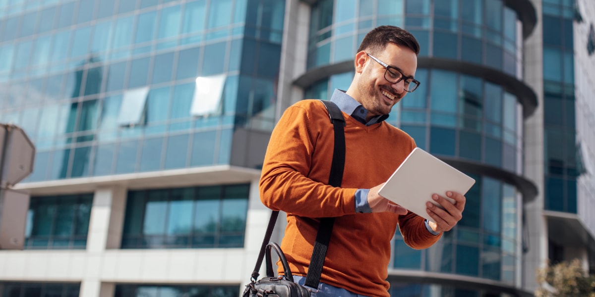 person-orange-sweater-looking-at-laptop-outside-booking