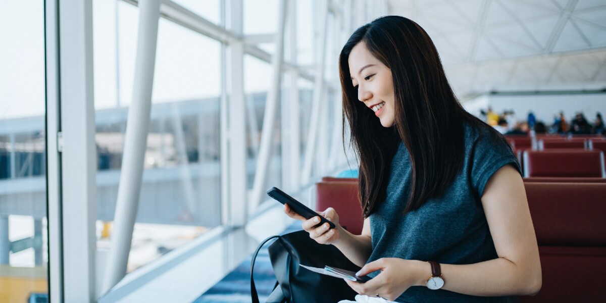 woman sitting in airport looking at mobile phone